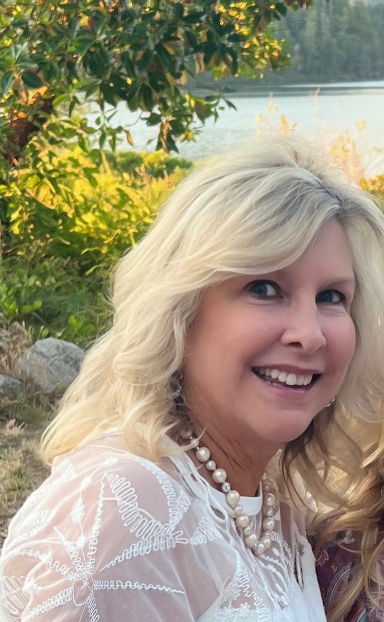 Smiling woman with blonde hair outdoors on a sunny day.